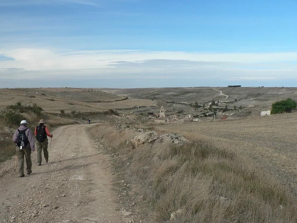 Dos peregrinos caminan a lo lejos por la meseta castellana hacia Hontanas