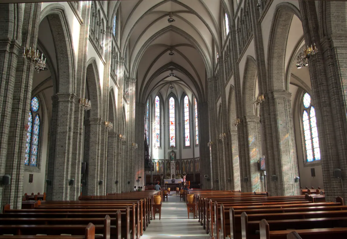 Nave interior de la Catedral de Myeongdong con vitrales y luz natural